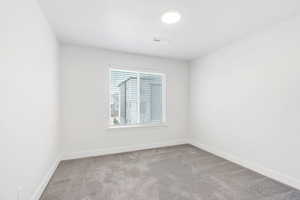 Unfurnished room featuring light carpet and baseboards