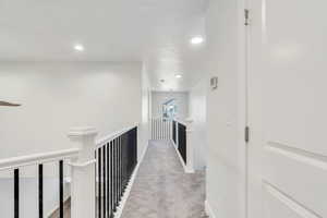 Corridor featuring an upstairs landing, light colored carpet, and recessed lighting