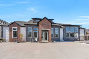 View of front of property featuring board and batten siding, a shingled roof, a patio area, and french doors
