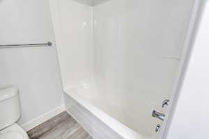 Bathroom with light wood-style flooring and bathing tub / shower combination