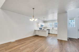 Kitchen featuring white cabinetry, a peninsula, a kitchen breakfast bar, a textured ceiling, and light wood finished floors