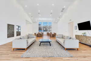 Living room with a high ceiling, light wood-style floors, and recessed lighting