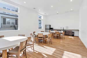 Dining area with light wood-style floors, recessed lighting, healthy amount of natural light, and a high ceiling