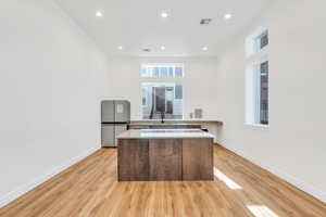 Kitchen featuring modern cabinets, light wood-type flooring, recessed lighting, freestanding refrigerator, and a center island