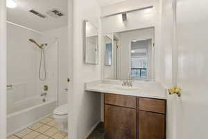 Bathroom with vanity, tub / shower combination, and light tile patterned floors