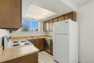Kitchen with white appliances, light countertops, light tile patterned floors, and wood finish cabinets