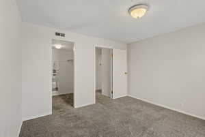 Unfurnished bedroom with a walk in closet, a textured ceiling, and carpet floors