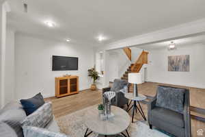 Living room with ornamental molding and wood finished floors