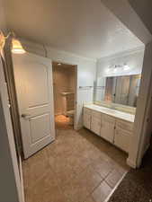 Full bath with vanity, a textured ceiling, light tile patterned floors, and crown molding