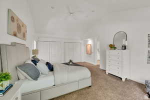 Bedroom with multiple closets, lofted ceiling, carpet, and a ceiling fan
