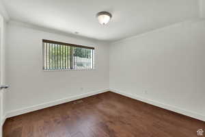 Spare room with dark wood-style floors and crown molding