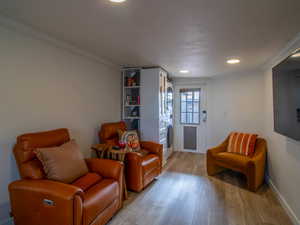 Sitting room featuring wood finished floors, recessed lighting, ornamental molding, and stacked washing machine and dryer