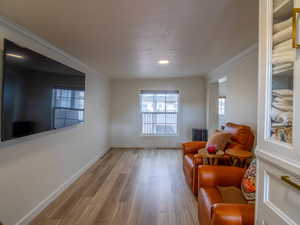 Living area featuring wood finished floors and crown molding