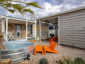 View of patio with a hot tub and an outbuilding