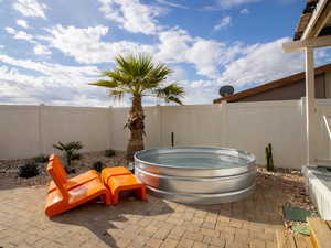 Fenced backyard featuring a hot tub and a patio