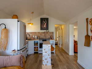 Kitchen featuring high quality appliances, dark wood-style floors, wooden counters, pendant lighting, and white cabinets