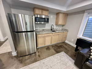Kitchen with stainless steel appliances, light stone counters, and light wood finish cabinets