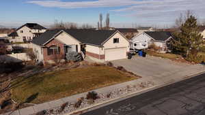 Single story home featuring a residential view, brick siding, concrete driveway, and stucco siding
