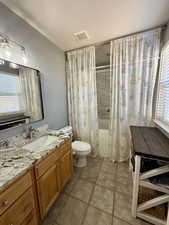 Bathroom with shower / tub combo with curtain, vanity, and light tile patterned floors