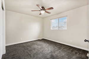 Spare room with dark colored carpet and ceiling fan
