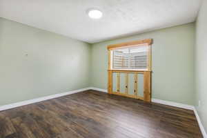 Spare room with dark wood-style flooring and a textured ceiling