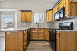 Kitchen with a peninsula, black appliances, light wood-style floors, light countertops, and tasteful backsplash