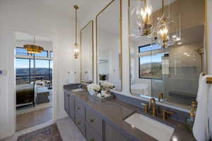 Full bathroom with connected bathroom, suspended lighting, a shower stall, and double vanity