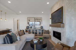 Living area with tile walls, a tiled fireplace, recessed lighting, and wood finished floors