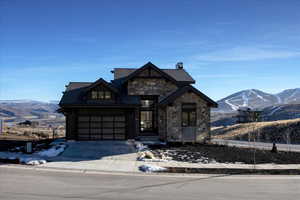 View of front of property featuring a mountain view, stone siding, and concrete driveway