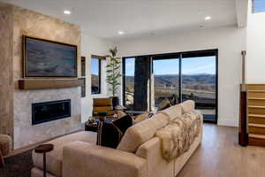 Living area with a tile fireplace, light wood finished floors, and recessed lighting