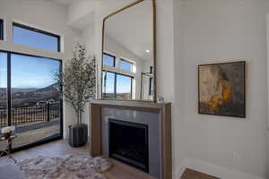 Living room with a fireplace, wood finished floors, a mountain view, a high ceiling, and recessed lighting
