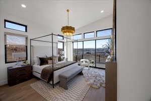 Bedroom featuring wood finished floors, vaulted ceiling, multiple windows, and a chandelier