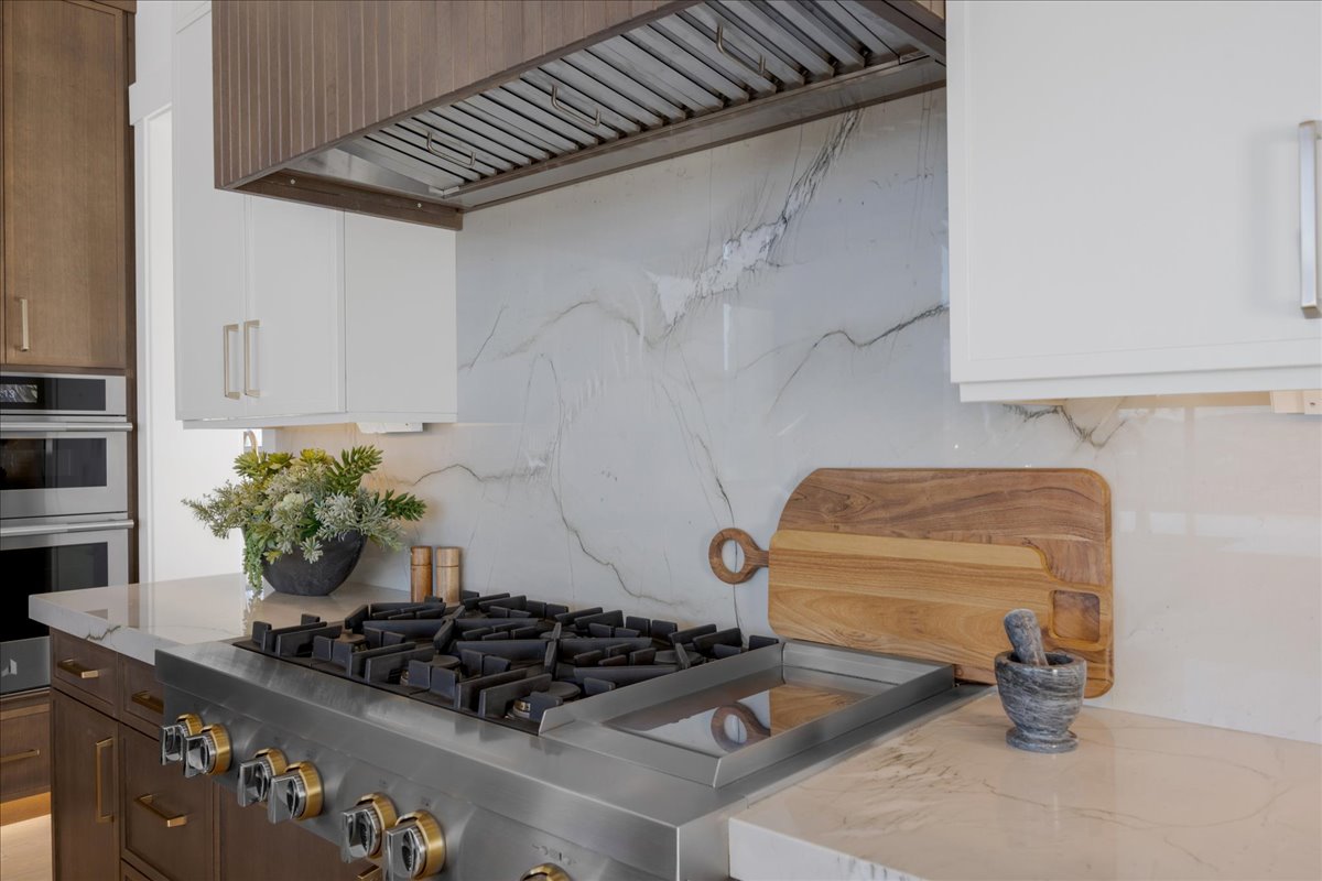 Dual tone kitchen with dual tone cabinetry, stainless steel appliances, and light stone counters