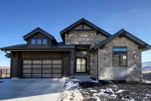 View of front of property featuring driveway, a garage, and stone siding