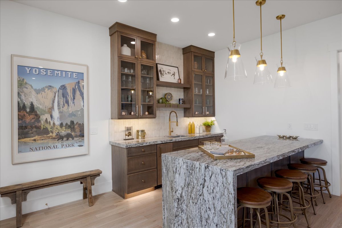 Bar featuring light wood-type flooring, decorative light fixtures, decorative backsplash, and glass insert cabinets