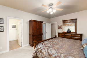 Bedroom featuring light colored carpet, ceiling fan, and ensuite bathroom