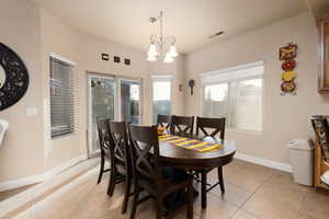 Dining area featuring light tile patterned floors, plenty of natural light, and a chandelier