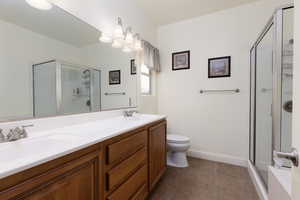 Bathroom with a stall shower, double vanity, and dark tile patterned floors
