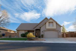 Traditional-style house with stone siding, driveway, stucco siding, and a tile roof
