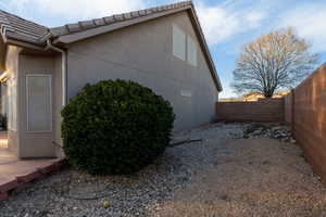 View of side of home with a fenced backyard and stucco siding