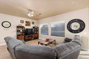 Living area featuring light wood-style flooring and ceiling fan