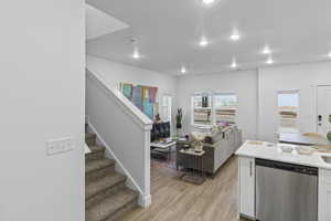 Kitchen with dishwasher, white cabinets, light wood-type flooring, open floor plan, and recessed lighting