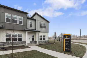 View of front facade with stone siding, a front lawn, and board and batten siding