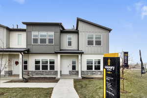View of front of house with stone siding, board and batten siding, and a front yard