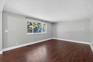 Empty room featuring baseboards and dark wood finished floors