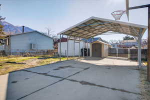 View of parking featuring a storage unit, a detached carport, driveway, and a mountain view