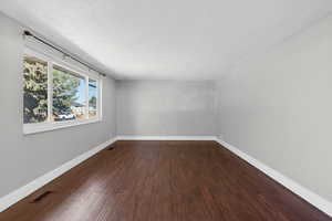 Spare room with dark wood-style flooring and baseboards