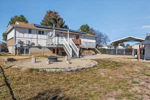 Back of house with a patio, roof mounted solar panels, a detached carport, a fire pit, and board and batten siding