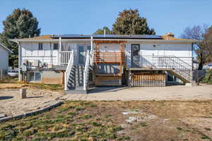 Rear view of property featuring roof mounted solar panels, a deck, and a chimney