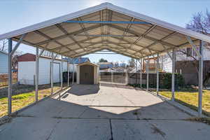 View of parking with a storage shed, a detached carport, and a residential view